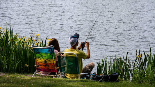 couple fishing from chairs side of lake